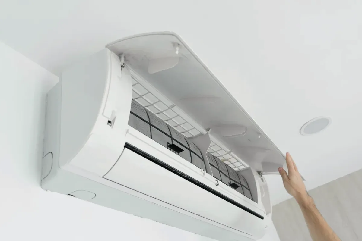 Hand opening the cover of a wall-mounted ductless air conditioner